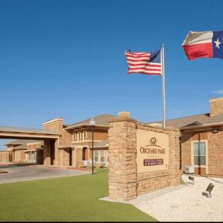 Exterior view of a hotel with American and Texas flags flying at the entrance.