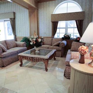A well-furnished living room featuring a sofa set, coffee table, and decorative indoor plants.