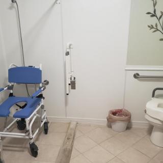 An accessible bathroom with a shower chair and grab bars for support.