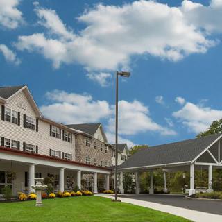 A spacious building with a well-maintained lawn under a bright blue sky with fluffy clouds.