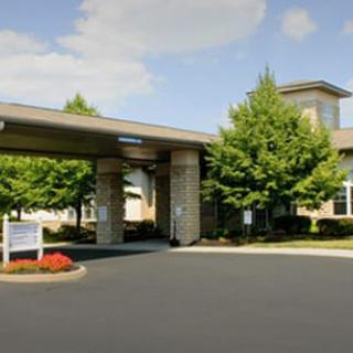 A building entrance with a covered driveway and surrounding trees.