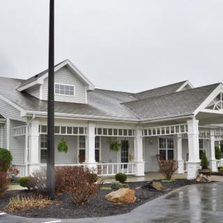 A white building with a porch and gabled roof on a rainy day.