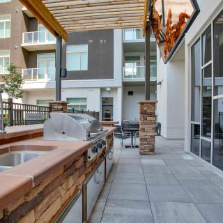 Modern outdoor patio with barbecue grill and seating area in an apartment complex.