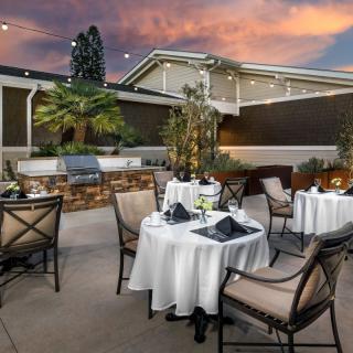 An elegant outdoor dining area with tables set under a vibrant sunset sky.