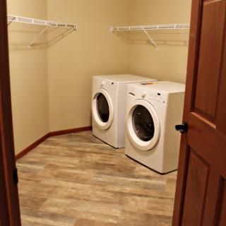 A well-organized laundry room featuring a washer and dryer along with storage shelves.