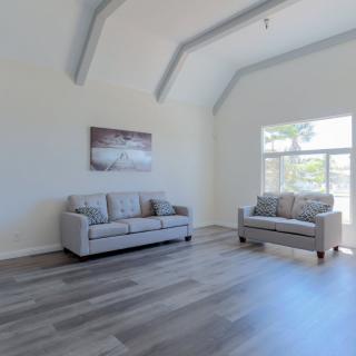 A modern minimalist living room with two grey sofas and bright natural lighting.