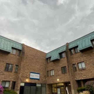 A three-story brick apartment building under a cloudy sky.