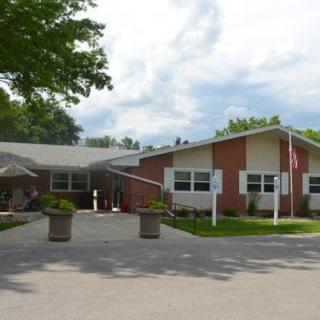 A nursing home building with a driveway and surrounding greenery.