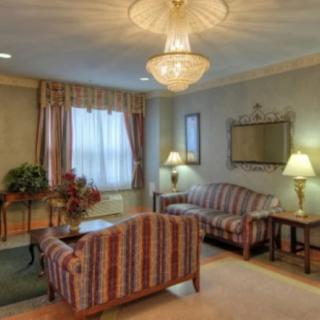 A cozy living room with a striped sofa, elegant chandelier, and decorative mirror, creating a warm and inviting atmosphere.