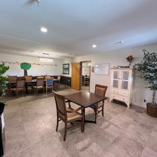 A spacious dining area featuring a wooden table with chairs, complemented by decorative plants and a welcoming atmosphere.