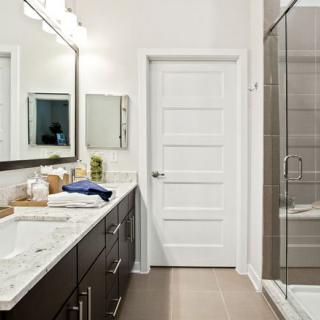 Modern bathroom with a sleek design featuring a double vanity, large mirror, and glass-enclosed shower.