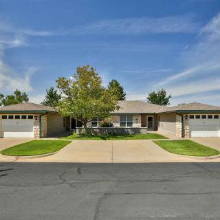 A suburban house with a well-maintained lawn and dual garages under a clear blue sky.