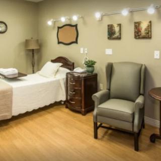 A cozy bedroom interior with a single bed, an armchair, and decorative elements on the walls.