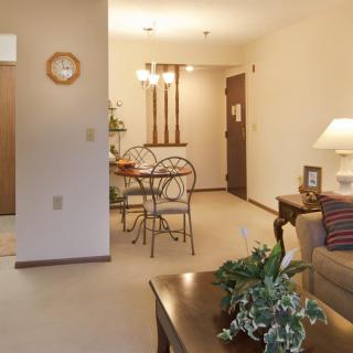 A cozy living room with a view of the dining area, featuring comfortable furniture and decorative plants.