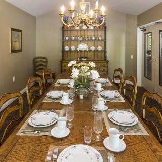 A formal dining room with an elegantly set table and a chandelier overhead.
