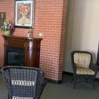A cozy indoor seating area with a decorative fireplace and wicker chairs.