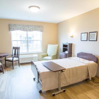 A well-lit and cozy bedroom setup featuring a bed, seating area, and small dining table.