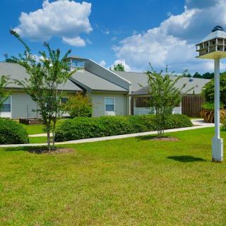 A charming residential property with a well-maintained lawn, garden, and birdhouse under a clear blue sky.