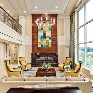A spacious and elegantly designed living room with a high ceiling, featuring a chandelier, modern artwork, and comfortable seating.