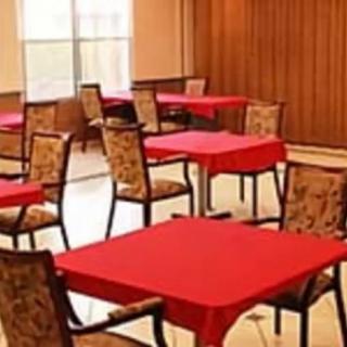 An empty dining area with tables covered in red tablecloths and patterned chairs.