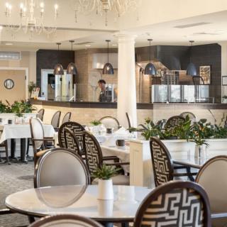 A modern restaurant interior with elegant dining tables and chairs, enhanced by decorative lighting and greenery.