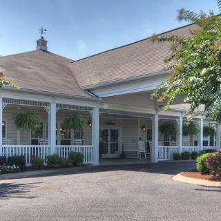 A building with a large porch and landscaped surroundings.