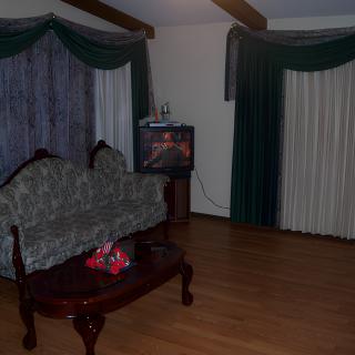 A cozy living room featuring a patterned couch, wooden coffee table, and a television set with large curtains.
