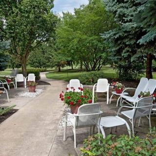 A serene garden setting with white chairs and lush greenery.