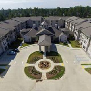Aerial view of a large apartment complex with landscaped gardens and driveways.