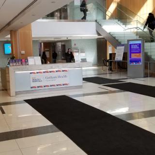 A spacious lobby featuring a reception desk and stairs leading to an upper level.