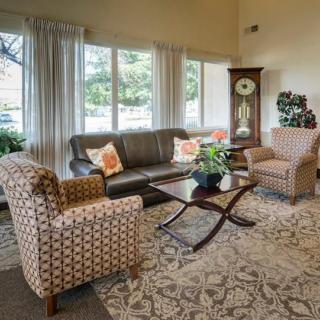 A cozy living room with a sofa, two patterned chairs, a coffee table, and decorations.