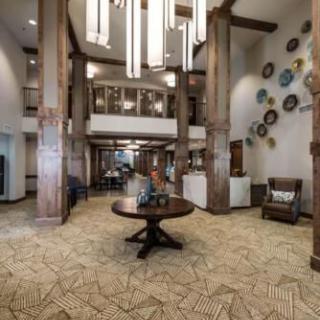 A spacious and elegantly designed hotel lobby featuring modern decor, large chandeliers, and wooden beams.