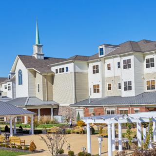 A modern building with a church steeple surrounded by landscaped gardens under a clear blue sky.