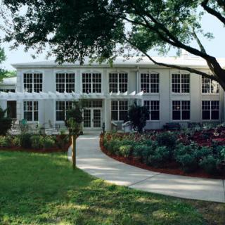 A two-story building with a well-maintained garden and pathway leading to the entrance.