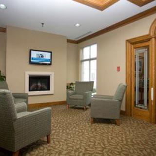 A cozy waiting room with comfortable chairs, a fireplace, and a television.