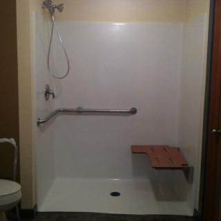 An accessible walk-in shower featuring a grab bar and foldable shower seat.