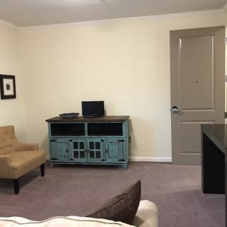A minimalist living room with a chair, computer on a cabinet, and a closed door.