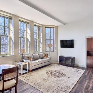 A modern living room featuring large windows, a comfortable sofa, and a stylish rug.