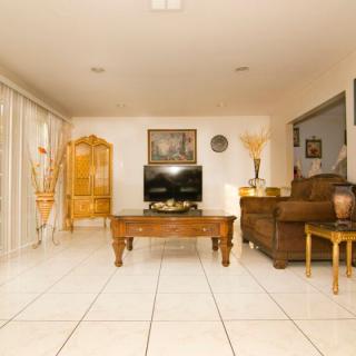 A cozy living room with a tile floor, featuring a television on a wooden stand, a coffee table, and comfortable seating.