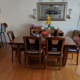 A cozy dining room with a wooden table and chairs, decorated with flowers and wall art.
