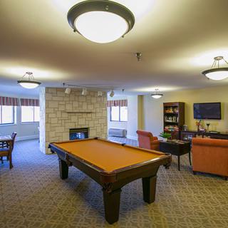 A cozy game room featuring a pool table, comfortable seating, and a fireplace.