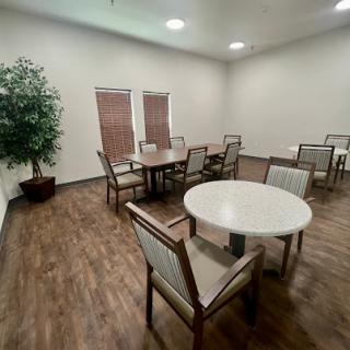 A spacious and well-lit interior room featuring tables and chairs, complemented by a decorative plant.