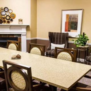 A well-appointed conference room with a long meeting table, upholstered chairs, decorative artwork, and a fireplace.