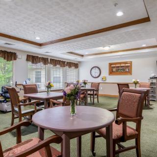 A well-lit dining area with multiple tables and chairs, featuring large windows and tasteful decor.