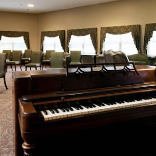 A well-lit interior featuring a piano and comfortable seating, creating a cozy atmosphere for music and gatherings.