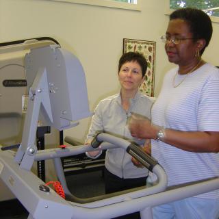 A person receives assistance during a treadmill workout as part of physical therapy.