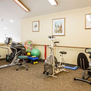 A small indoor gym featuring various exercise equipment including stationary bikes, a treadmill, yoga mats, and exercise balls.