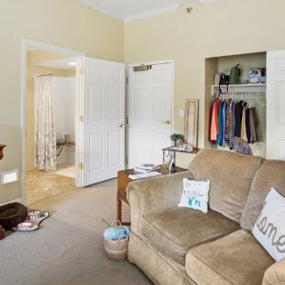 A cozy living room with a sofa and an open closet, showcasing organized home decor.