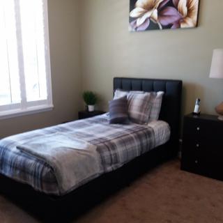 A cozy bedroom with a single bed, nightstand, and a decorative wall painting.