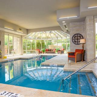 A luxurious indoor swimming pool with modern furniture and large glass walls offering outdoor views.